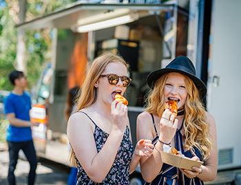 Two girls eating from a food truck